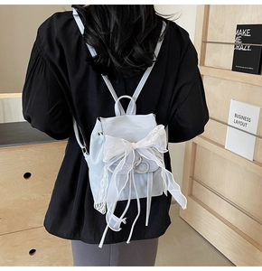 Detail of light blue mini backpack with white lace bow and drawstring on matte leather