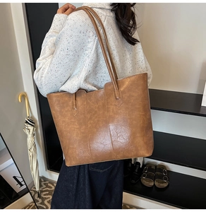 Macro view of brown large tote bag showing textured synthetic leather and vertical stitching