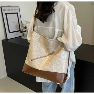 Close-up of beige and brown large tote bag featuring lychee texture and metal zipper