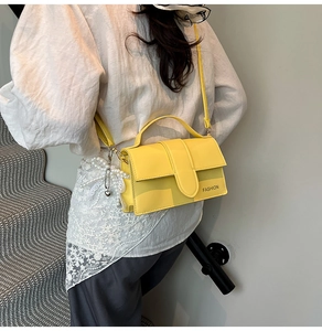 Close-up of bright yellow leather handbag with fashion logo and pearl lace charm