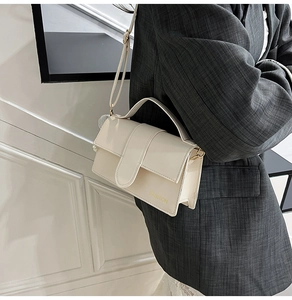 Detail view of cream white minimalist crossbody bag on a striped suit blazer outfit