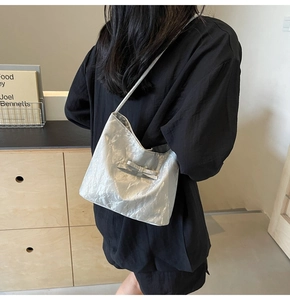 Détail du sac seau plissé argenté avec nœud porté à l'épaule sur le mannequin