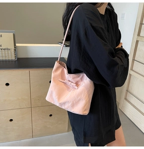 Détail d'un sac seau en tissu plissé rose clair avec une décoration de nœud épuré