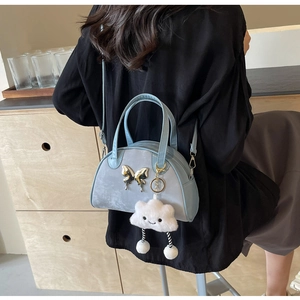 Détail du sac bandoulière bleu clair avec boucle papillon argentée et pendentif nuage