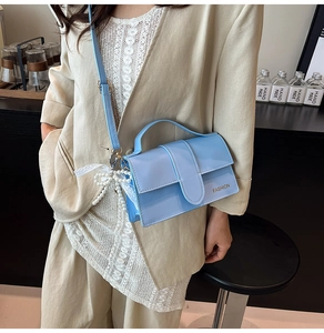 Detail of light blue square crossbody bag featuring pearl lace charm and fashion logo