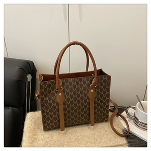 Close-up of vintage brown monogram pattern tote bag with leather straps and gold rivets