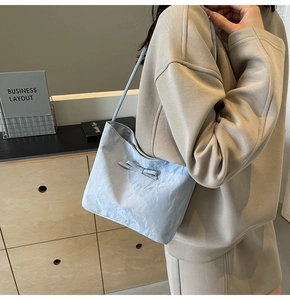 Détail du sac seau bleu clair avec nœud décoratif et texture plissée en tissu léger