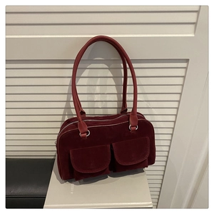 Detail of burgundy suede shoulder bag with dual front pockets and leather handles