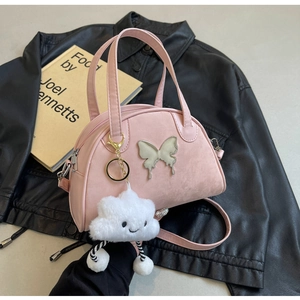 Détail du sac à main demi-lune rose avec boucle papillon et breloque nuage en peluche
