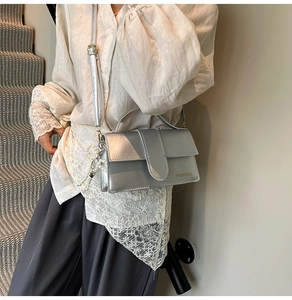 Detail of a silver metallic crossbody bag with pearl chain and FASHION logo on a model