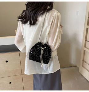Detail of black sequin bucket bag featuring pearl drawstring and silver chain strap