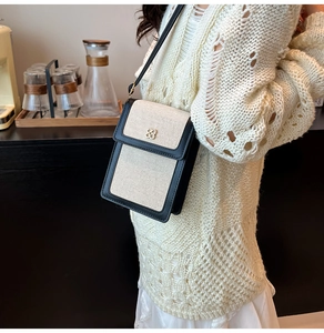 Close-up of black and white canvas mini crossbody bag with flower metal buckle detail