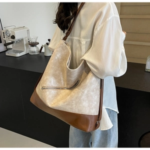 Detail shot of a large beige and brown tote bag with textured finish and front zipper