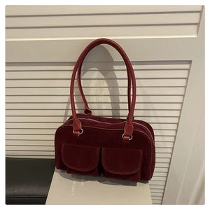 Detail of burgundy suede shoulder bag featuring two front pockets and silver zipper