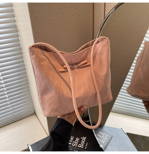 Détail du sac seau plissé rose avec nœud décoratif et anses souples pour porter à l'épaule