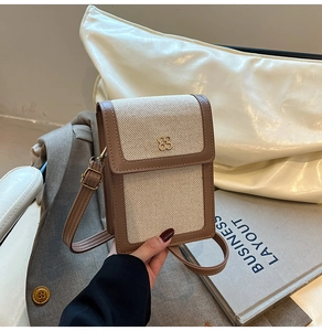 Detailed shot of canvas crossbody bag with brown leather trim and golden clover clasp