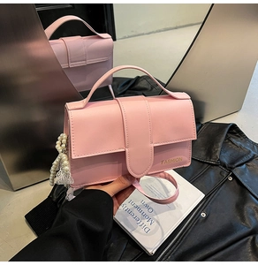 Detailed shot of pink PU leather crossbody bag with fashion text and pearl lace pendant