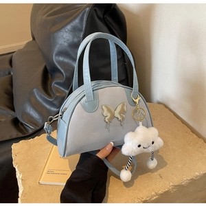 Détail du sac bowling bleu clair avec accent papillon argenté et breloque nuage