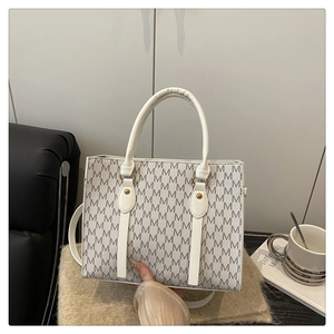 Detail of white structured tote bag featuring grey M-letter print and round handles