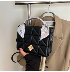 Détail du sac à main noir matelassé avec fermoir doré et foulard en soie à motif paisley