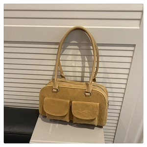 Close-up of yellow suede shoulder bag featuring dual front flap pockets and zip closure