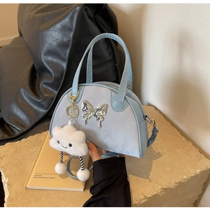 Détail du sac bandoulière bleu clair avec boucle papillon argentée et charme nuage en peluche