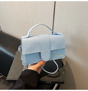 Close-up of light blue leather handbag featuring a fashion logo and gold hardware details