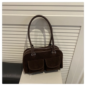 Detail of dark brown suede shoulder bag with twin front pockets and silver hardware