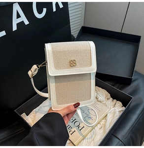 Detail of white square crossbody bag with clover gold buckle on black background