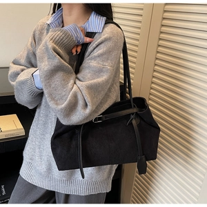 Detail of black suede tote bag with double straps and silver metal buckles