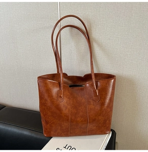 Detail of vintage brown leather tote bag showing oil-wax texture and double shoulder straps