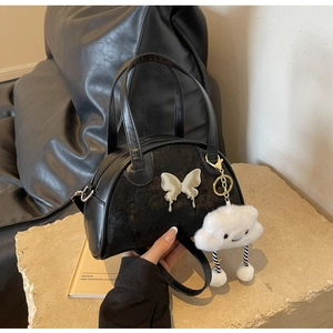 Détail du sac à main en cuir noir avec papillon argenté et pendentif nuage blanc duveteux