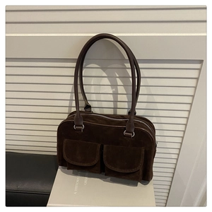 Detail of dark brown suede shoulder bag with dual front pockets and silver zipper