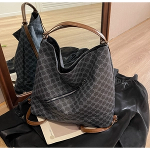 Detailed view of large tote bag with geometric clover patterns and brown leather straps