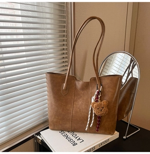 Brown faux leather tote bag detail with cute teddy bear charm and striped ribbon accent