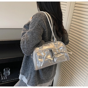 Détail d'un sac argenté métallisé avec nœuds et texture effet miroir porté à l'épaule