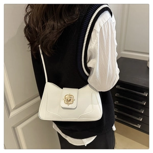 Detail of white leather shoulder bag featuring a gold floral-shaped metal buckle