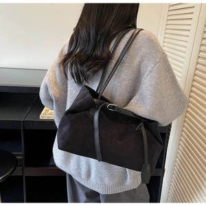 Detail of black suede tote bag with slim leather straps and elegant front buckle strap