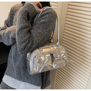 Sac à bandoulière argenté métallisé avec nœuds décoratifs et poches porté par le modèle