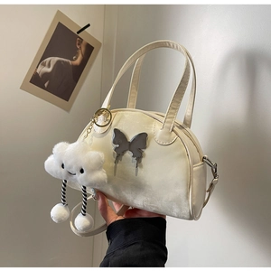 Gros plan d'un sac à main carré crème avec papillon argenté et porte-clés nuage