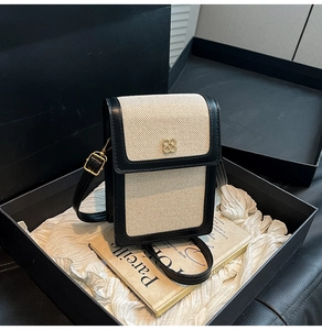 Detail of a chic black and white crossbody bag with gold flower hardware in a gift box
