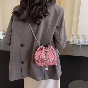 Pink sequin bucket bag with silver chain strap and pearl drawstring details shown on model