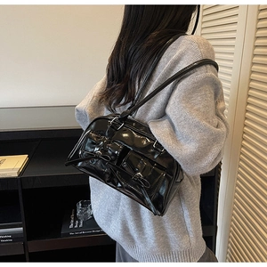 Detail of black patent leather shoulder bag with silver buckles and bow accents