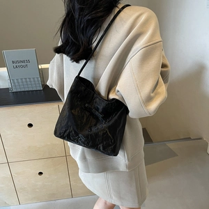Sac à épaule noir plissé brillant avec détail nœud dans un cadre moderne épuré