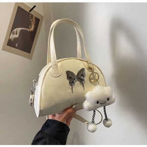 Détail du sac beige en croissant avec papillon métallique et breloque nuage doux