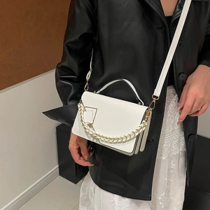 French minimalist white crossbody bag with gold lock and chain strap on female model