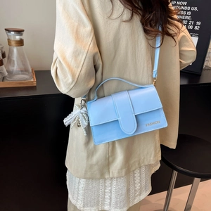 Light blue faux leather crossbody bag with pearl bow charm and gold logo detail
