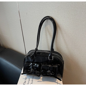 Detail of glossy black patent leather tote with decorative bows and flap pockets