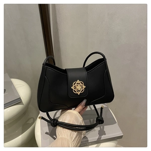 Détail d'un sac à bandoulière en cuir noir mat avec un fermoir floral doré chic