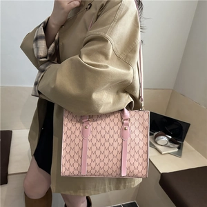 Pink monogram square crossbody bag with top handle and gold hardware on a stylish model
